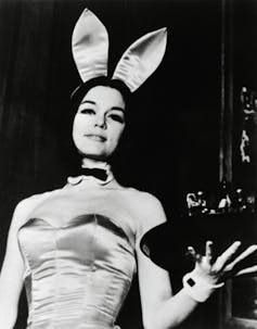 A woman in a Playboy Bunny costume, holding a tray of drinks